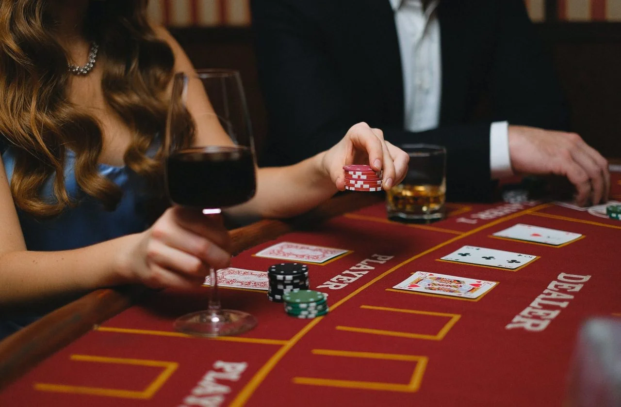 elegant man and woman playing poker in a casino and drinking wine